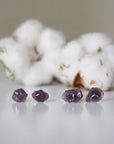Two pairs of raw amethyst stud earrings showing natural variation in stone size, shape, and color, sterling silver posts