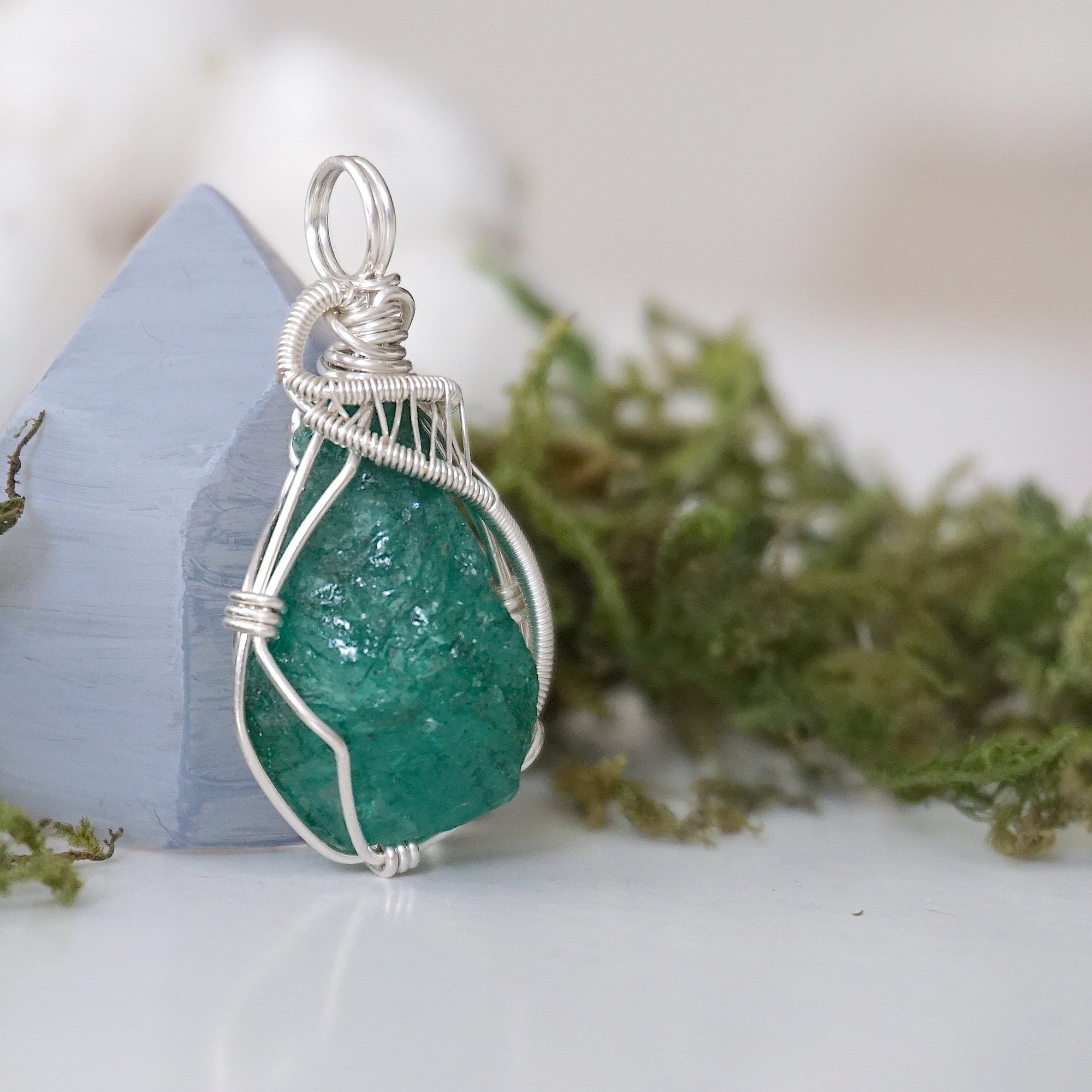 Right angle detail of raw emerald pendant for women showing natural emerald and artisan 925 sterling silver wire wrapping