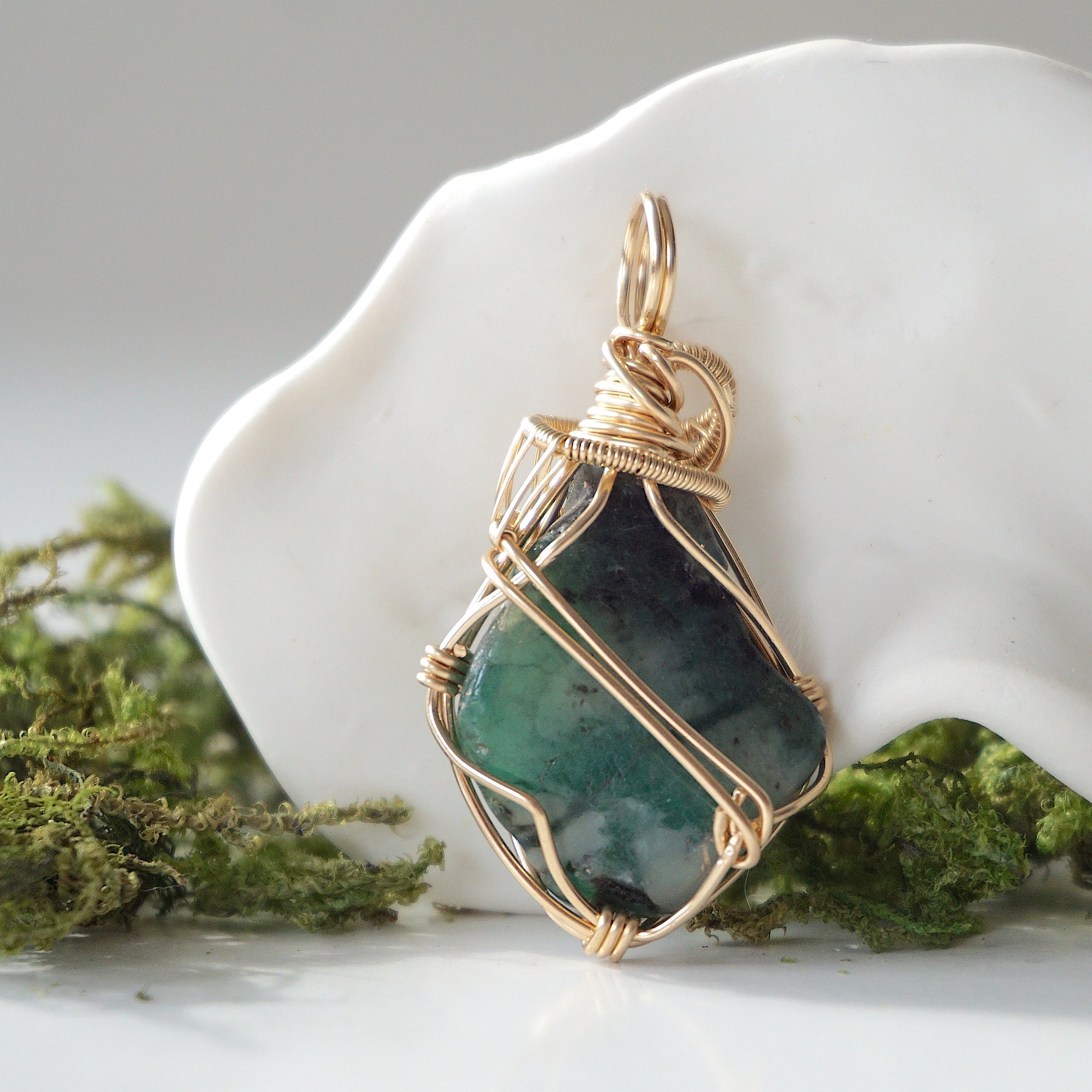 Back view of raw emerald pendant showing detailed artisan wire wrapping in 14k gold-filled wire.