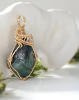 Right angle view of raw emerald pendant showing detailed handcrafted wire wrapping in 14k gold-filled wire.