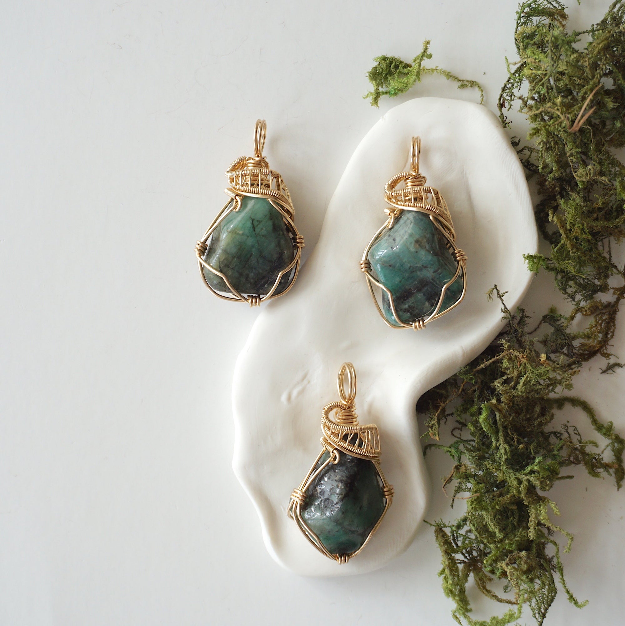 Three raw emerald pendants showing natural variation in size, shape, and green colour by Designs by Nature Gems.