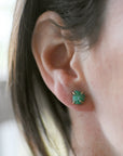 Female model wearing raw emerald stud earrings in 14k gold vermeil with natural emerald stones and minimalist design