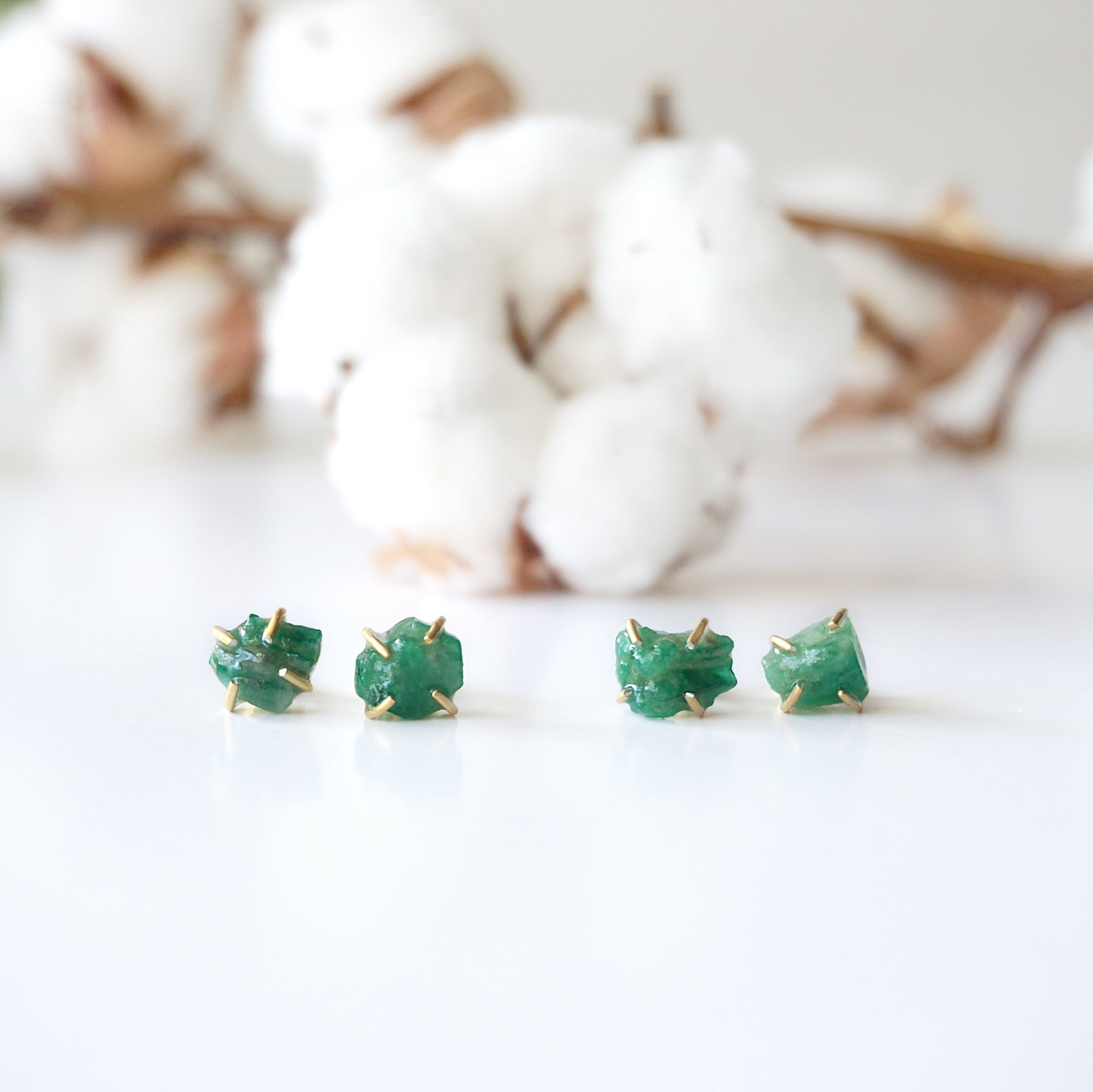 Two pairs of raw emerald stud earrings in 14k gold vermeil showing natural variation in emerald shape size and green colour