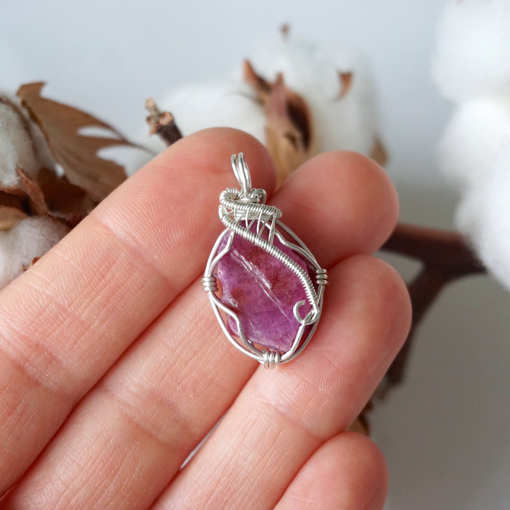 Raw pink ruby pendant in hand for size reference, sterling silver artisan wire wrapped necklace