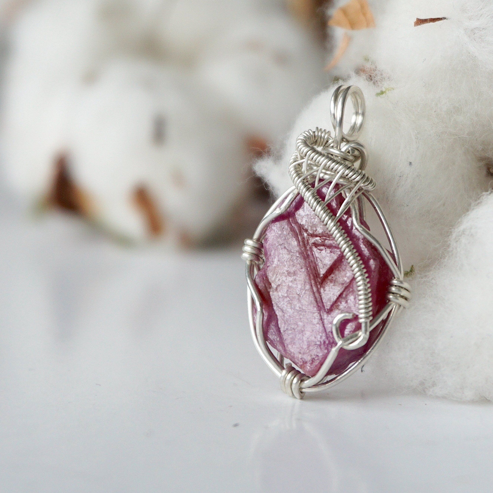 Side angle of raw ruby pendant, sterling silver artisan wire wrapping, showing detail and craftsmanship
