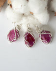 Three raw ruby pendants showing natural variation in color, size, and shape, sterling silver artisan wire wrapped