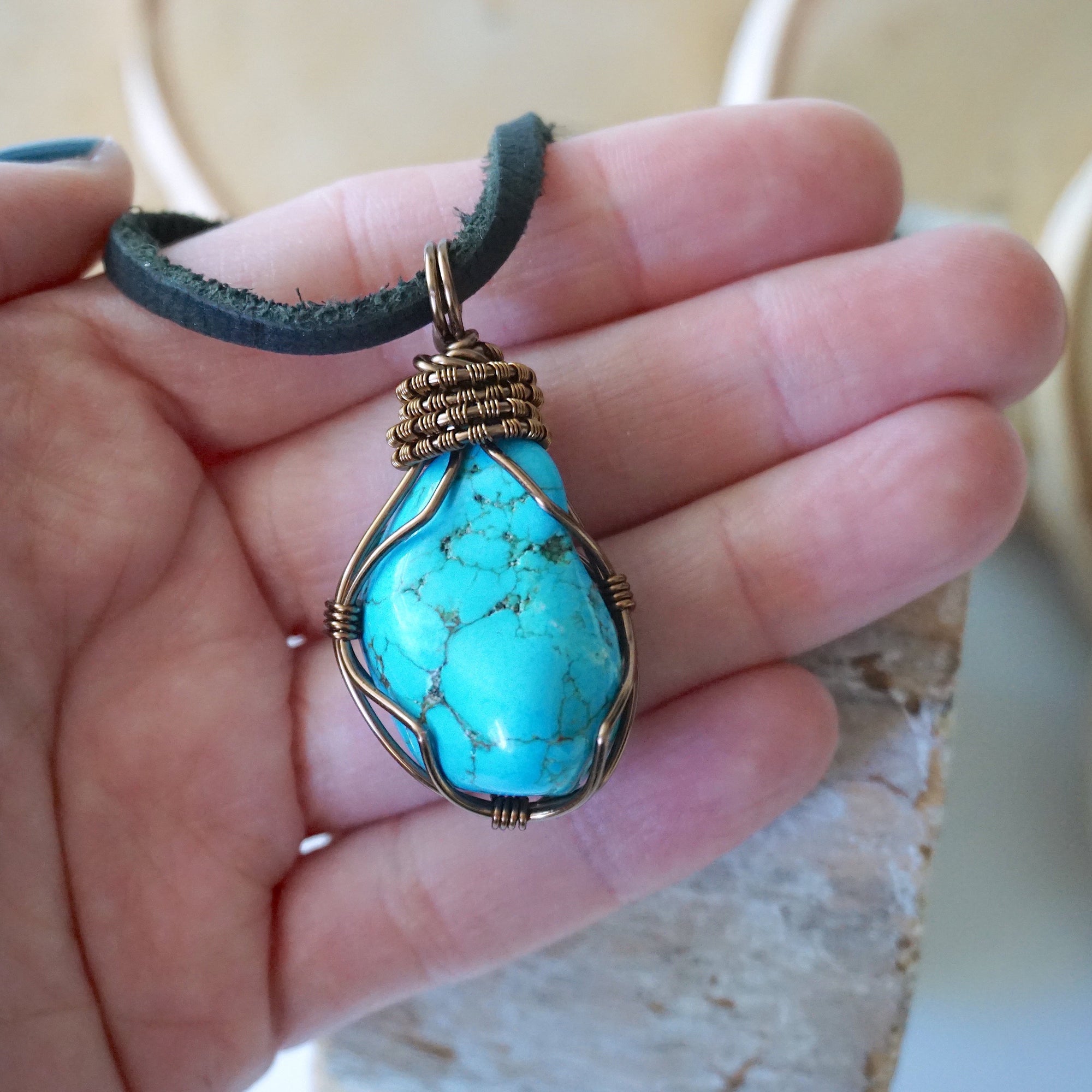 Raw turquoise pendant for men size reference in hand on black leather cord
