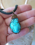 Raw turquoise pendant for men size reference in hand on black leather cord