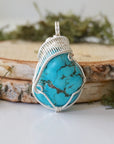 Front view raw turquoise pendant with detailed silver wire wrapping art