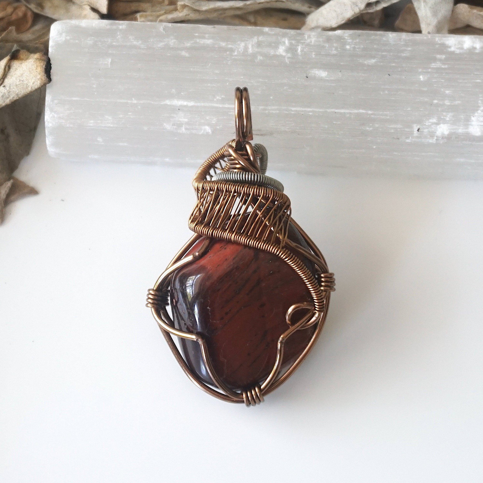 Detailed view of natural red tiger's eye pendant, artisan wire wrapped by Designs by Nature Gems.
