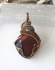 Detailed view of natural red tiger's eye pendant, artisan wire wrapped by Designs by Nature Gems.