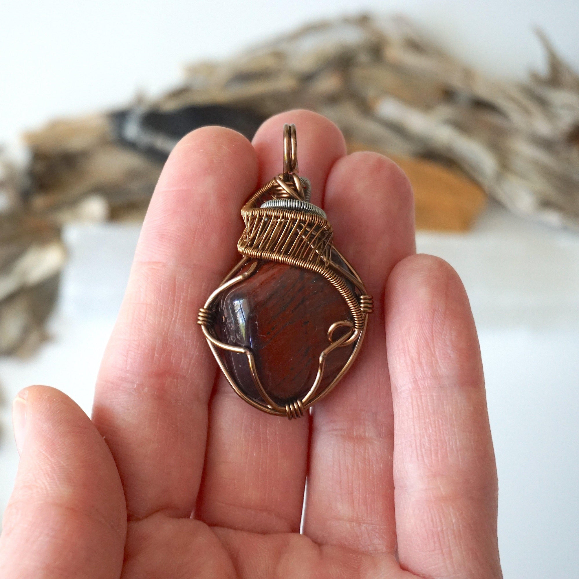 Natural red tiger's eye pendant in hand for size reference, handcrafted by Designs by Nature Gems.