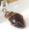 Right side angle detail of natural red tiger's eye pendant, wire wrapped by Designs by Nature Gems.