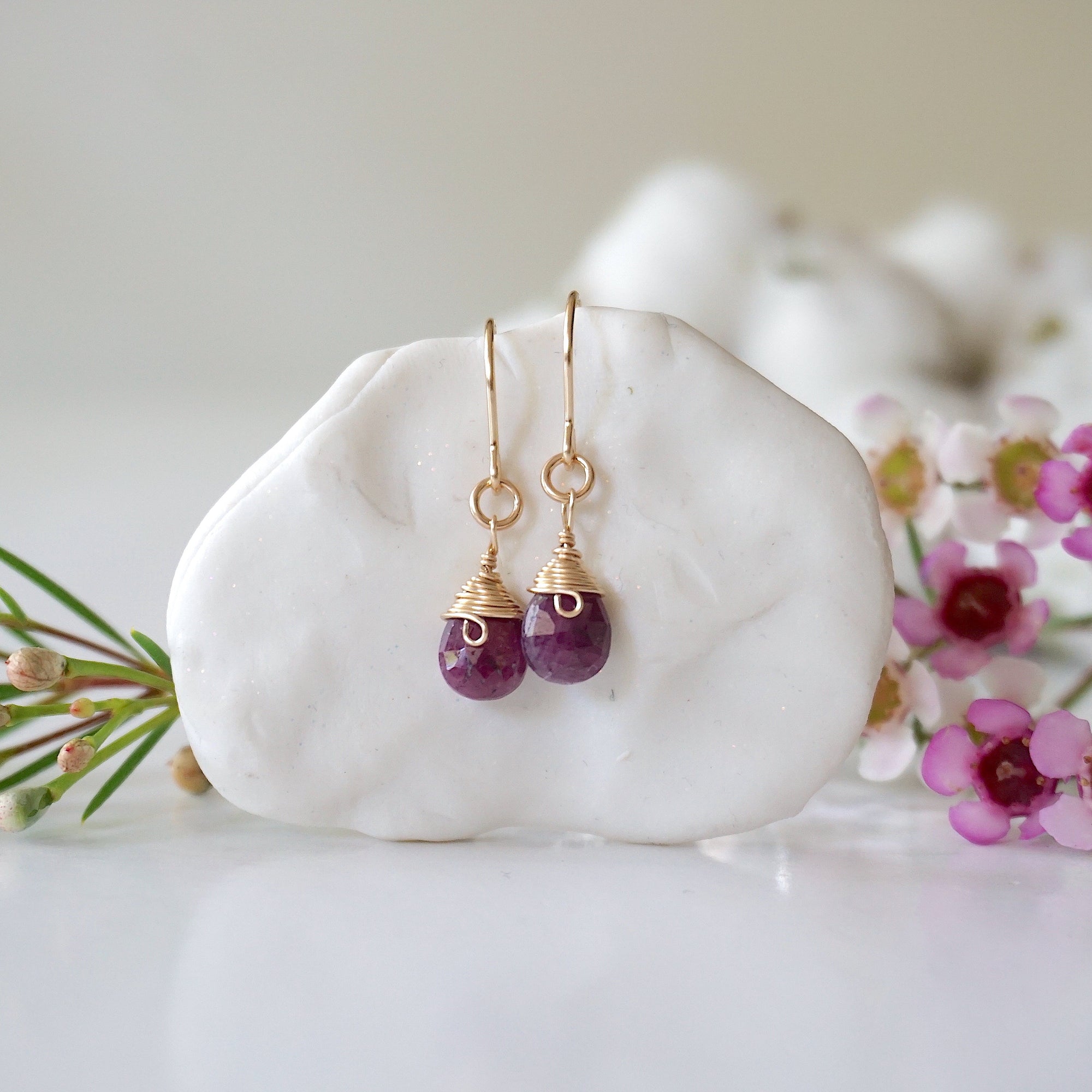 Detailed front view of ruby drop earrings, genuine faceted ruby with minimalist 14k gold filled wire wrapping, Designs by Nature Gems