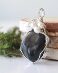 Side angle of handmade shungite and freshwater pearl pendant necklace, silver wire wrapped jewelry
