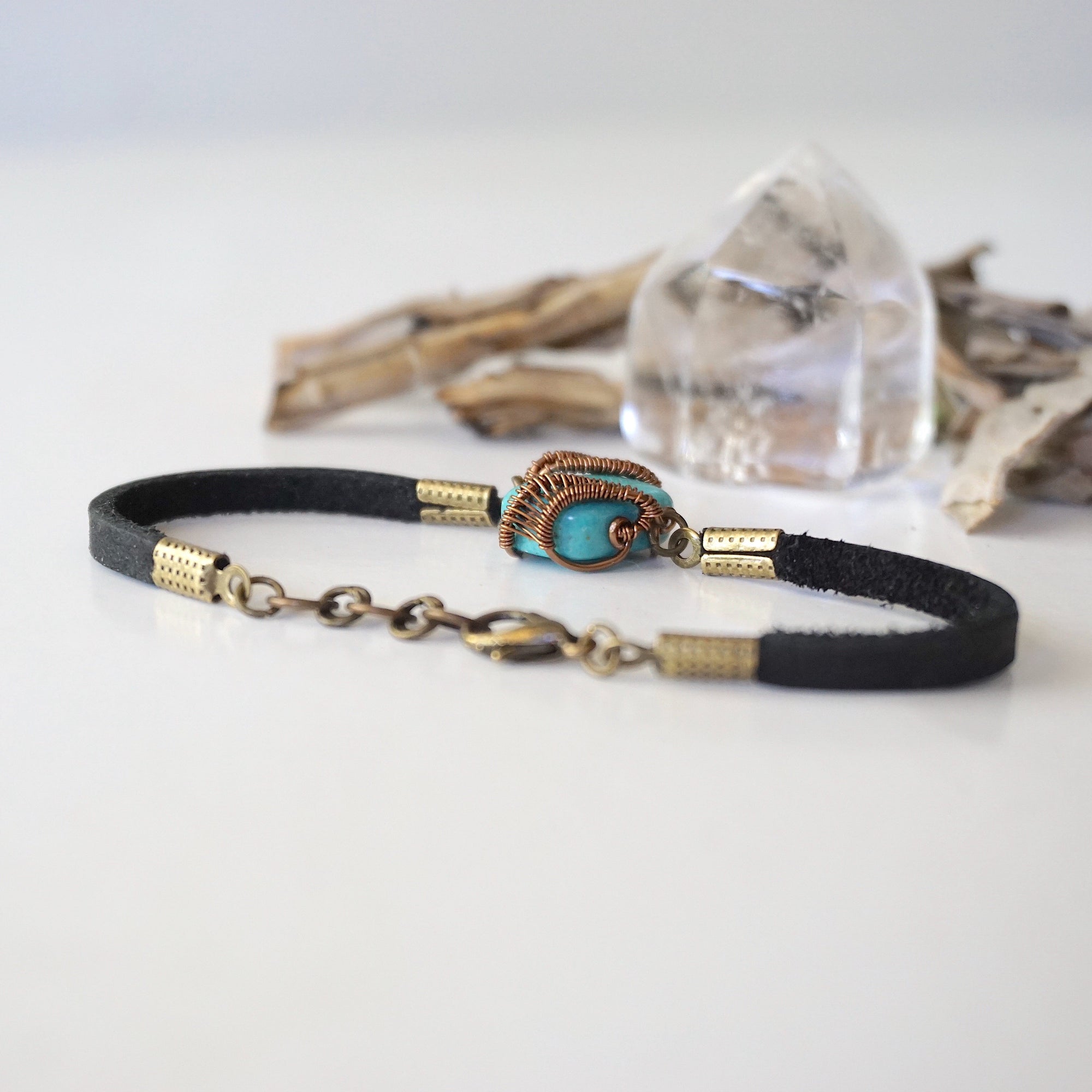 Back view of turquoise bracelet showing antique bronze wire wrapping technique and adjustable leather strap closure, 0.5 inch extension