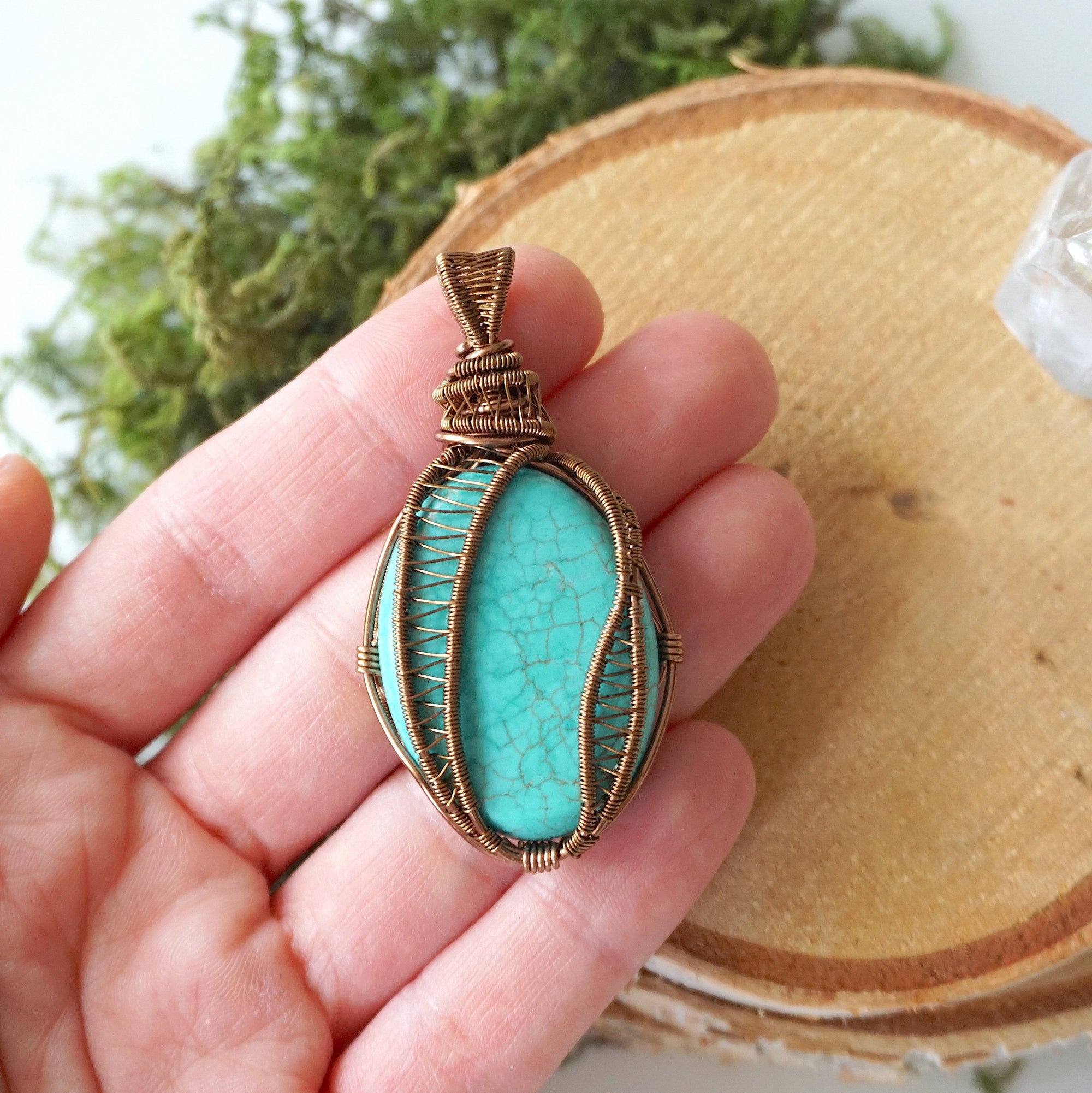 Turquoise pendant necklace held in hand showing size reference and scale of natural stone with bronze wire wrapping