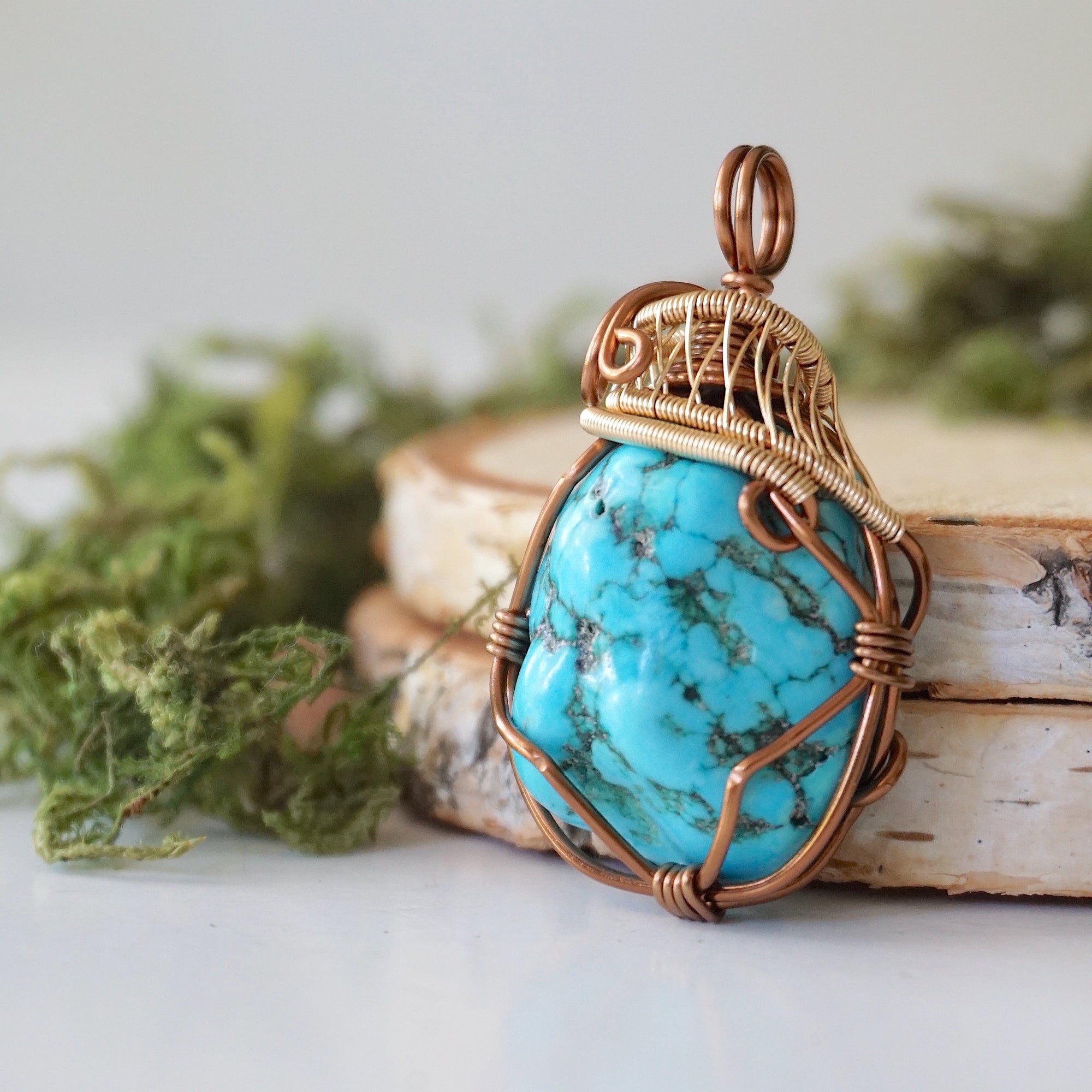 Side angle turquoise pendant showing wire wrap depth and mixed metal art