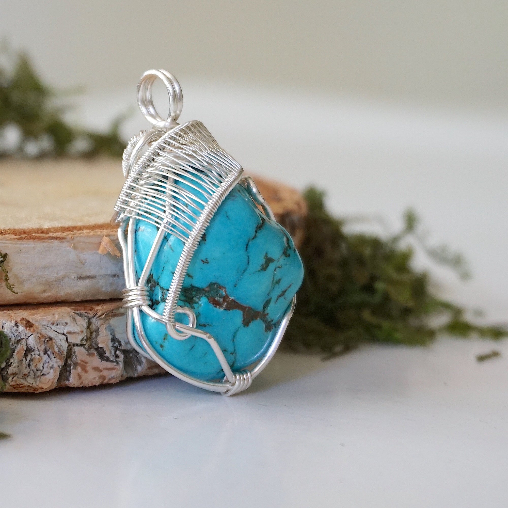 Side angle turquoise pendant showing wire wrap depth and artisan detail