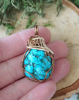 Mixed metal turquoise pendant size in hand showing bronze gold wire detail
