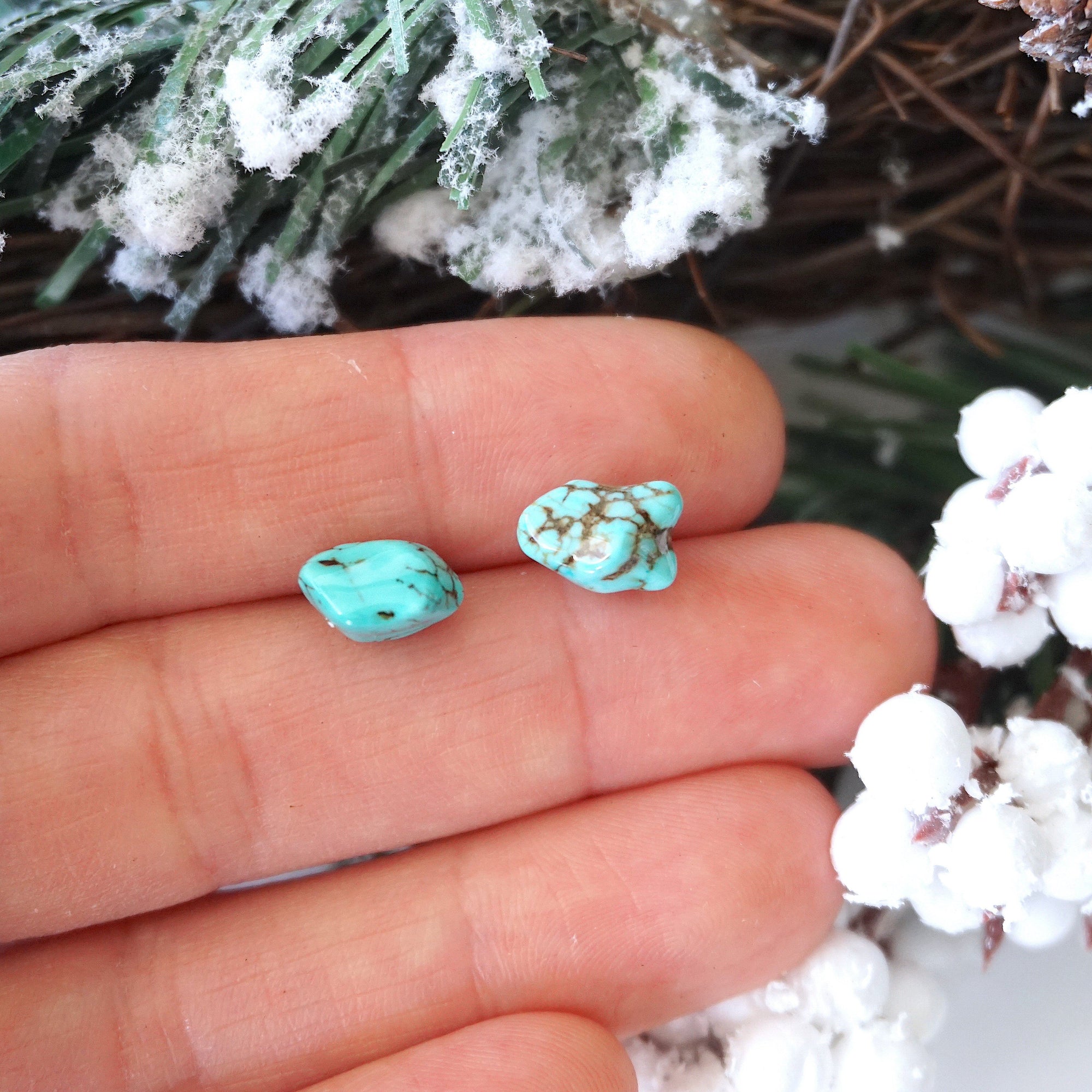 Turquoise stud earrings held in hand showing size reference - approximately 6-9mm natural stones with sterling silver posts