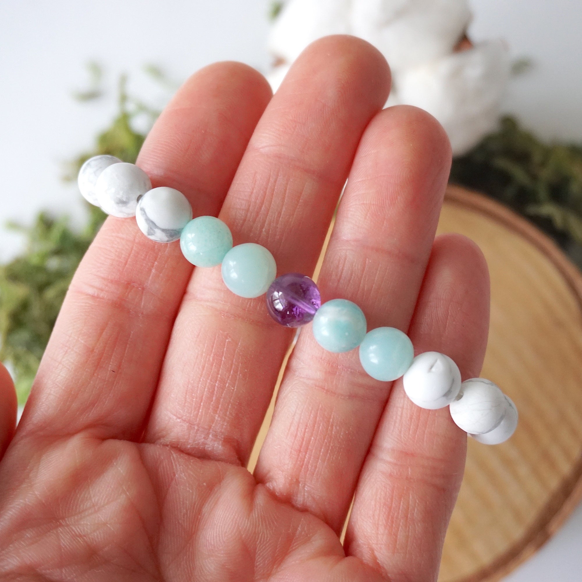 Bracelet in hand showing detailed view of white howlite, amethyst, and amazonite beads, natural crystal stretch bracelet