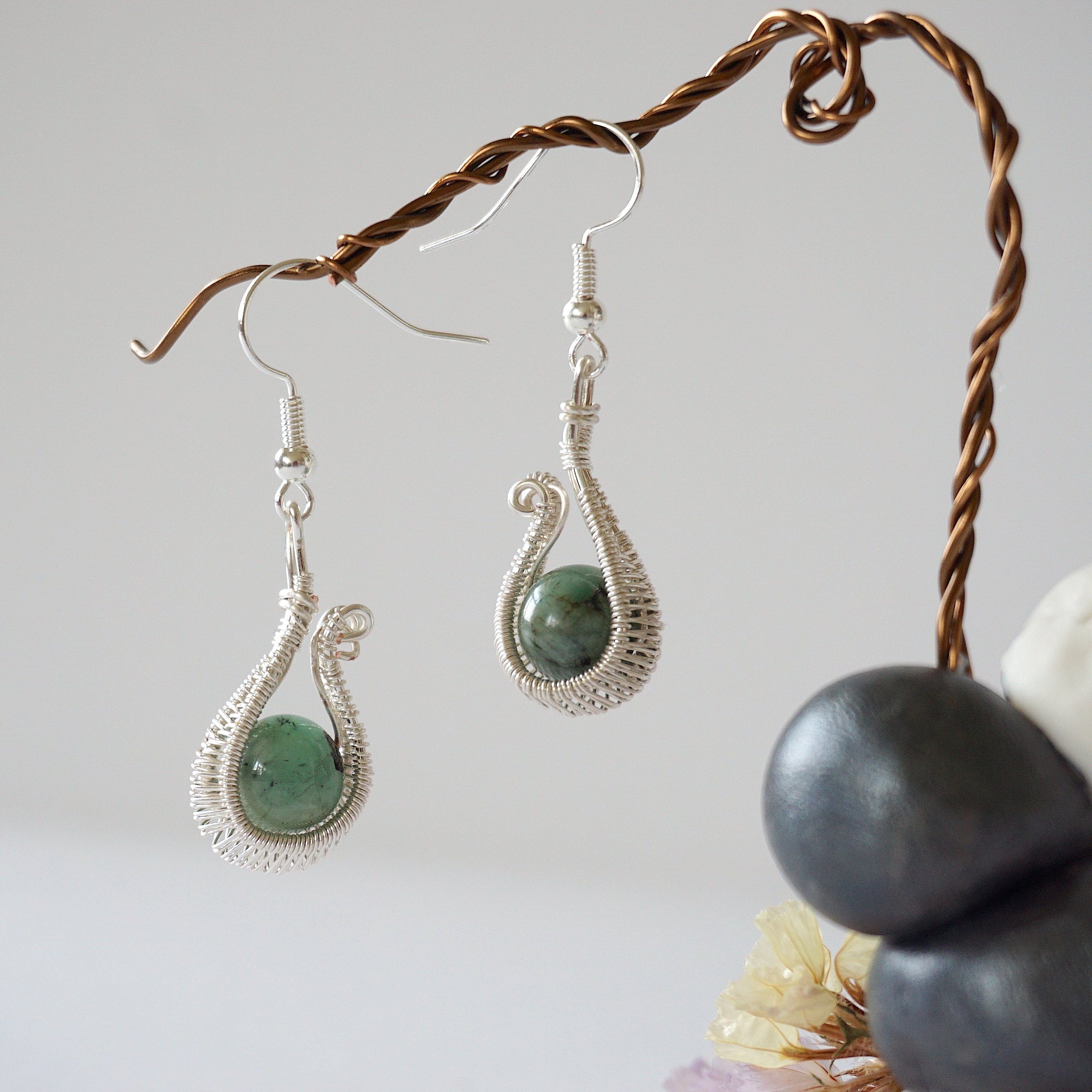 Side angle view of wire wrapped emerald drop earrings in soft silver copper with natural emerald bead and elegant drop shape