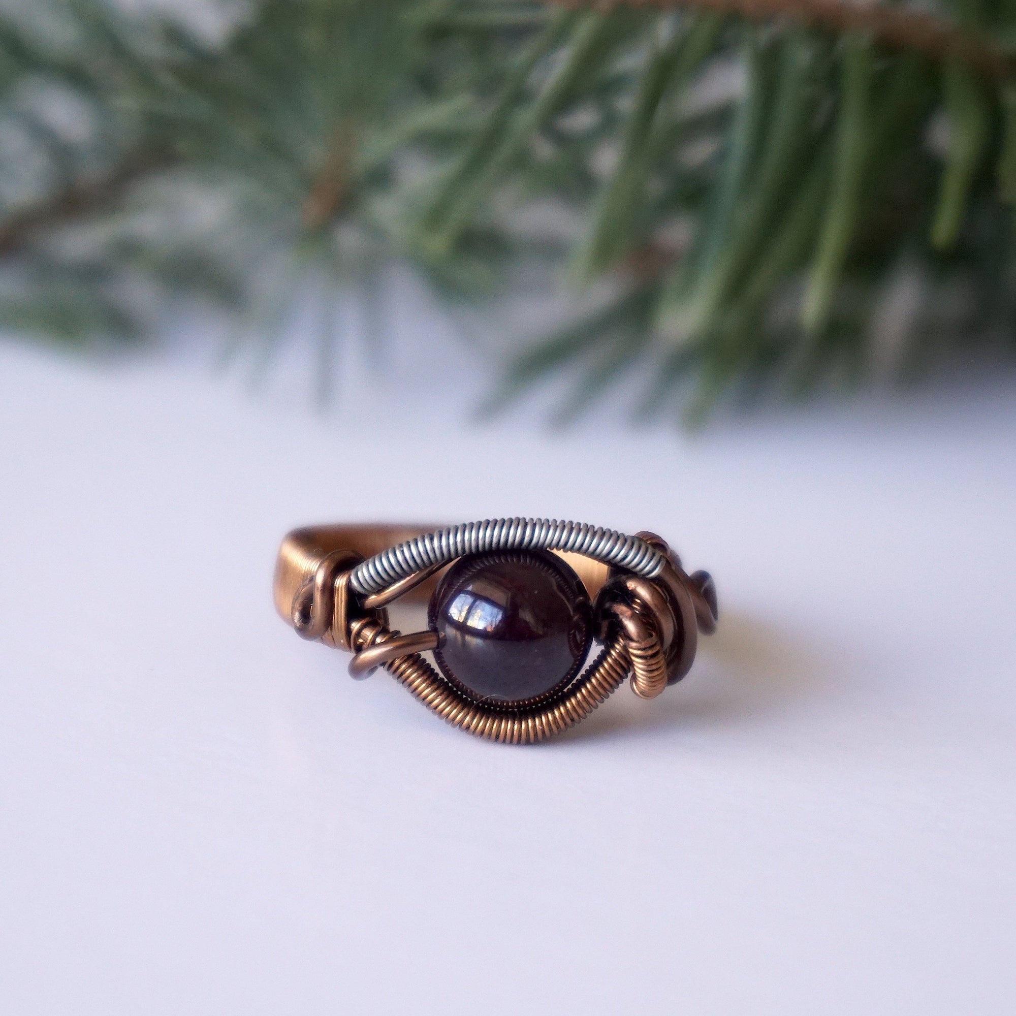 Front angle view of a wire wrapped garnet ring featuring an 8mm garnet crystal bead and mixed metal wire