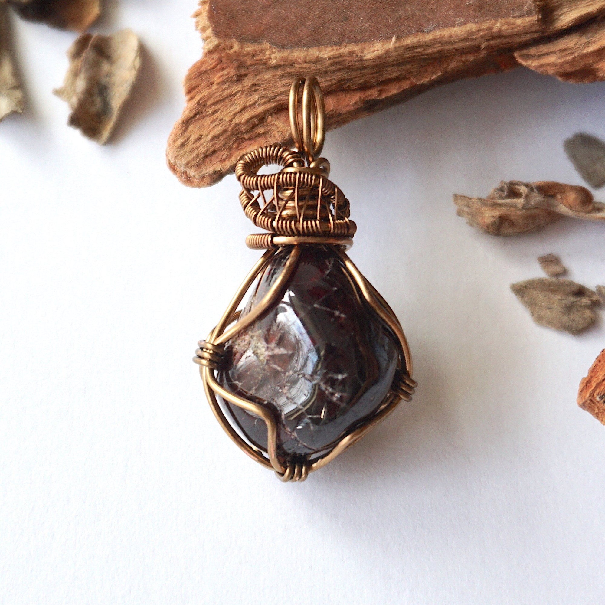 Front angle view of a women’s garnet wire wrapped pendant in antique bronze copper, showcasing the natural garnet and handcrafted wire work