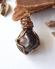 Front angle view of a women’s garnet wire wrapped pendant in antique bronze copper, showcasing the natural garnet and handcrafted wire work