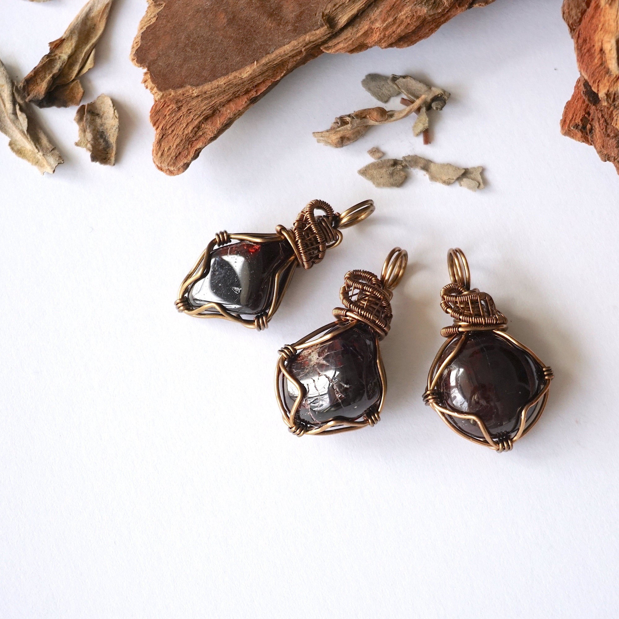 Three natural garnet pendants showing variation in size, shape, and color, allowing customers to choose their women’s wire wrapped garnet necklace