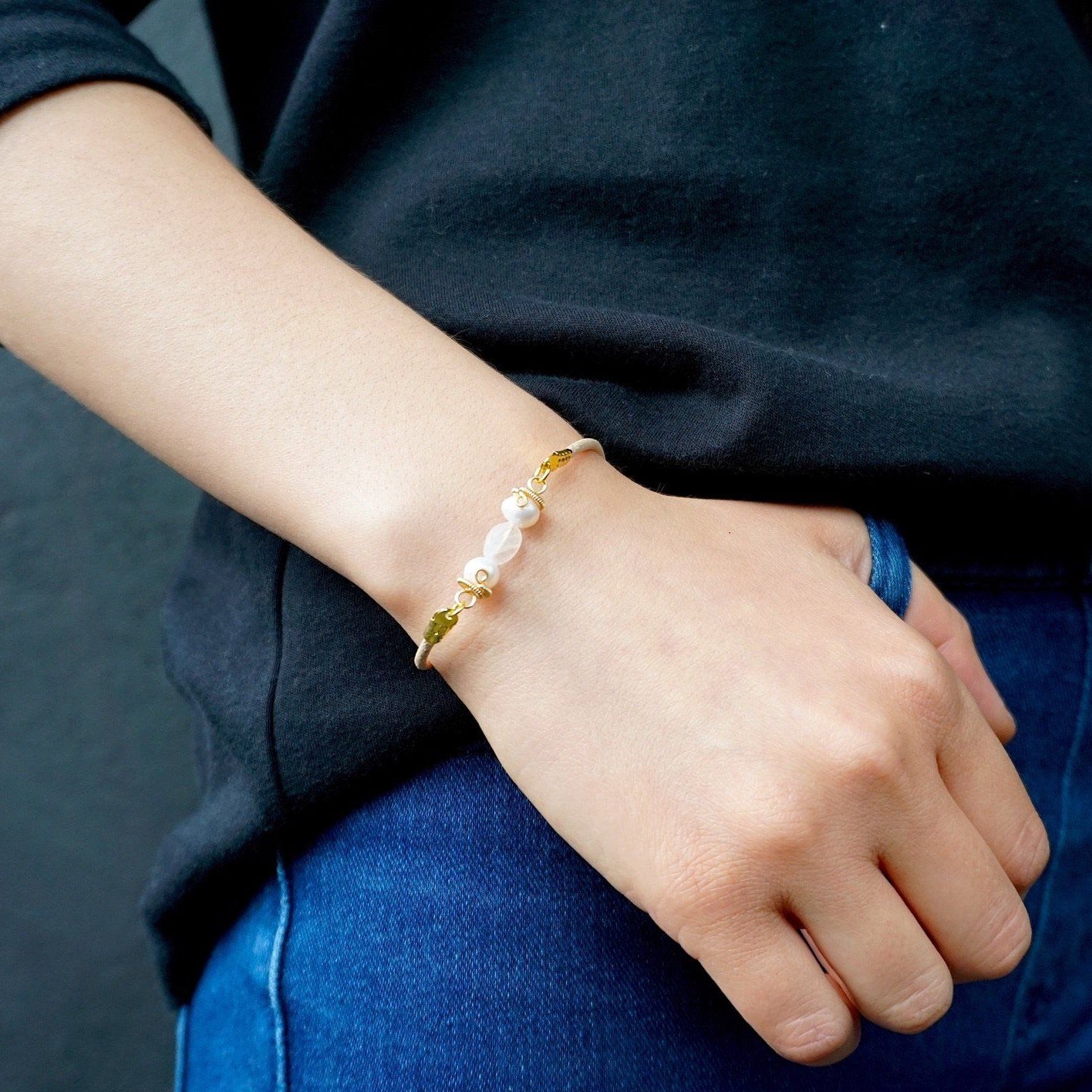Women’s pearl and moonstone leather bracelet worn on a female model’s wrist, featuring freshwater pearls and rainbow moonstone